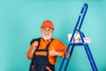 Repair. senior man painter use roller on ladder. painting the wall in blue. professional painter in working clothes Royalty Free Stock Photo