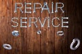 Repair service text made of screws and nut on the wooden background