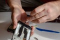 Repair of smartphones concept. A man unscrews the screws fixing the display from the board. Part of a series