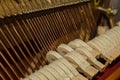 Repair of a stringed musical instrument. Inside view of a piano with brass metal strings and a wooden mallet. A musical