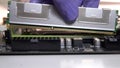 The repair technician inserts a RAM stick into the socket on the motherboard. Maintenance and modernization of a