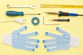 Repair tools on a yellow background. Measuring tape, screwdriver, construction gloves. Flat lay. Top view. Handyman tool