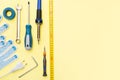 Repair tools on a yellow background. Measuring tape, screwdriver, construction gloves. Place for text. Copy space. Flat