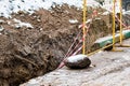 Repair of underground utilities in winter. Ditch in ground, fenced off with grate. Abandoned construction site. Royalty Free Stock Photo