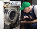 Repair of washing machines, large household appliances. The master examines the disassembled washing machine and records