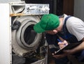 Repair of washing machines. A technician examines an old broken washing machine and records Royalty Free Stock Photo
