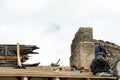 Repair of a wooden roof and an old brick chimney pipe. Workers in special clothing perform life-threatening work at high altitude Royalty Free Stock Photo