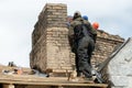 Repair of a wooden roof and an old brick chimney pipe. Workers in special clothing perform life-threatening work at high altitude Royalty Free Stock Photo