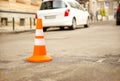 Repair work sign restricting traffic. White-orange plastic striped cone warning of danger. Tightening in traffic. Street of the