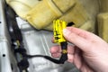 Repairing automotive electrical wiring. An auto electrician holds a connector of the car& x27;s electrical wiring in