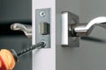 Repairing the door lock in the room using a screwdriver yourself. Close-up. Selective focus. Royalty Free Stock Photo