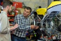 repairing motorcycle in workshop with coleague