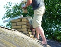 Repairing And Rebuilding A Brick Chimney. A Building Contractor Is Repair Chimney On A House Rooftop With Asbestos Roof