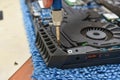 Repairing vent part of gaming laptop and fitting with mini screwdriver on blue table
