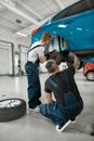 Repairing your vehicle. Full length shot of two male mechanics using torch for examining car wheel brake disc of lifted Royalty Free Stock Photo