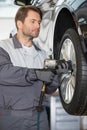 Repairman adjusting car's wheel in workshop