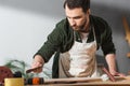 Repairman in apron holding sandpaper near