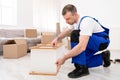 Repairman Assembling Furniture In Flat After Relocation, Wearing Blue Coverall