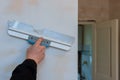 Repairman check the evenness of the wall using a wide spatula