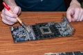 Repairman cleaning disassembled graphics card with brush
