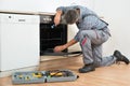 Repairman Examining Oven With Flashlight