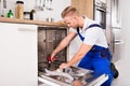 Repairman Fixing Dishwasher In Kitchen Royalty Free Stock Photo