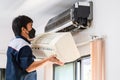 Repairman fixing modern air conditioner, Male technician cleaning air conditioner indoors, Maintenance and repairing concepts Royalty Free Stock Photo