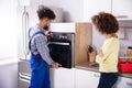 Repairman Fixing Oven In Kitchen Royalty Free Stock Photo