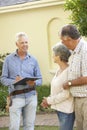 Repairman Giving Senior Couple Estimate For Roof Repair