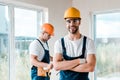 Repairman in goggles standing with crossed arms near coworker Royalty Free Stock Photo