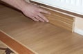 Skirting Board & Architrave. Repairman hands Installing Skirting Board Oak Wooden Floor with Glue. Flooring and Repair. Royalty Free Stock Photo