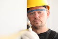 Repairman in helmet and mask, measures tape measure
