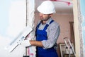 Repairman in helmet plastering wall with putty