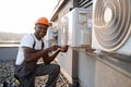 Repairman holding screwdriver and fixing conditioner outdoor