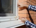 Repairman installing mosquito wire screen on house window. Royalty Free Stock Photo