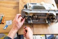 Repairman master is testing old disassembles sewing machine in workshop repairing it sitting at table Royalty Free Stock Photo