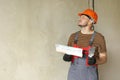 repairman in overalls and protective orange helmet holds two spatulas for plastering concrete wall with putty using Royalty Free Stock Photo