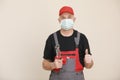 repairman and plumber in protective mask giving a thumbs up, he is holding an adjustable wrench. Male worker with repair Royalty Free Stock Photo