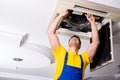 The repairman repairing ceiling air conditioning unit