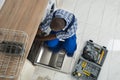 Repairman Repairing Dishwasher In Kitchen