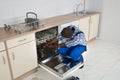 Repairman Repairing Dishwasher In Kitchen Royalty Free Stock Photo