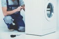 Repairman is repairing a washing machine on the white background Royalty Free Stock Photo