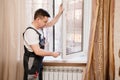 a repairman repairs, adjusts or installs metal-plastic windows in the apartment. Royalty Free Stock Photo