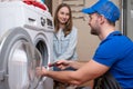 Repairman repairs a washing machine in front of a woman. A man communicates with the owner of a washing machine Royalty Free Stock Photo