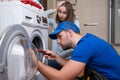 Repairman repairs a washing machine in front of a woman. A man communicates with the owner of a washing machine Royalty Free Stock Photo