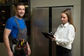 Repairman shows fixed refrigerator to woman in kitchen