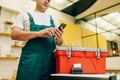 Repairman in uniform holds phone against toolbox Royalty Free Stock Photo