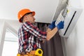 Repairman using a screwdriver fixing modern air conditioner, Male technician cleaning air conditioner indoors Royalty Free Stock Photo