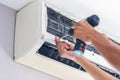 Repairman using a screwdriver fixing modern air conditioner, Male technician cleaning air conditioner indoors, Maintenance and Royalty Free Stock Photo