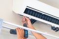 Repairman using a screwdriver fixing modern air conditioner, Male technician cleaning air conditioner indoors, Maintenance and Royalty Free Stock Photo